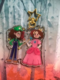 Glittery Game Grumps acrylic charms with a matching glittery sticker