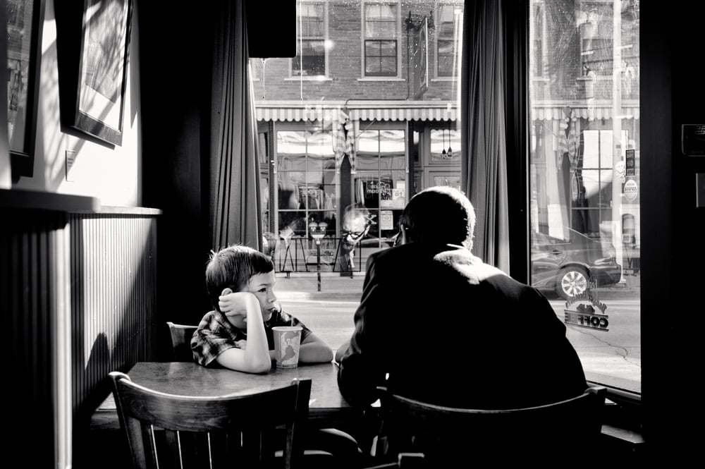 Image of boy listening to the man reflected in the window