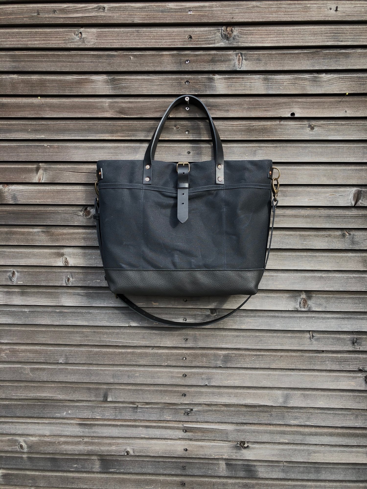 Image of Black tote bag in waxed canvas with leather bottom and cross body strap