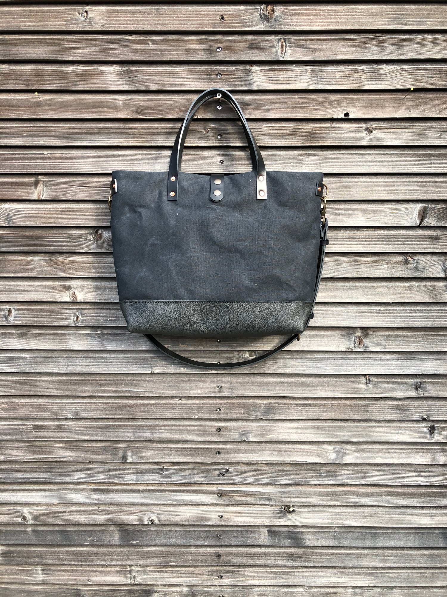 Image of Black tote bag in waxed canvas with leather bottom and cross body strap