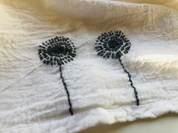 Image of twin dandelions in grey on white towel
