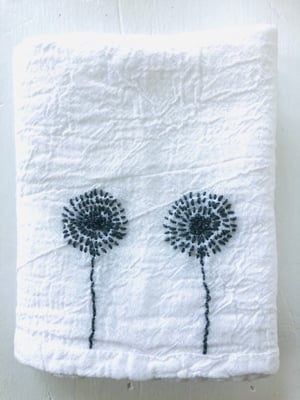 Image of twin dandelions in grey on white towel
