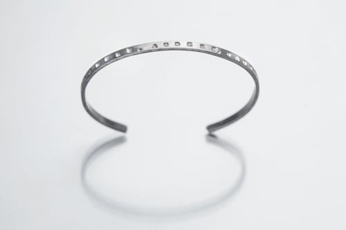 Image of thin silver bracelet with inscription in Latin