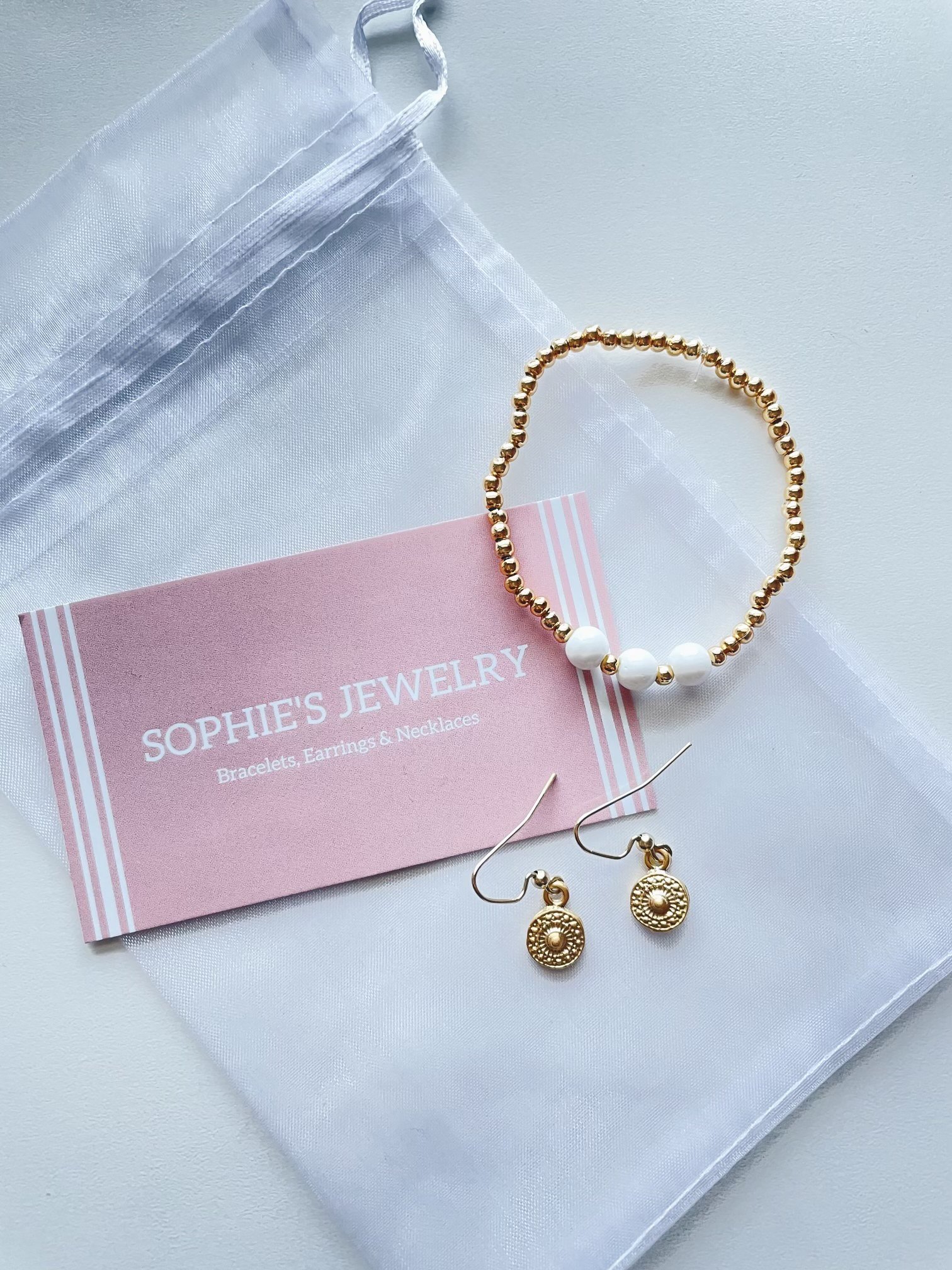 Image of gold earrings and gold and white bracelet 