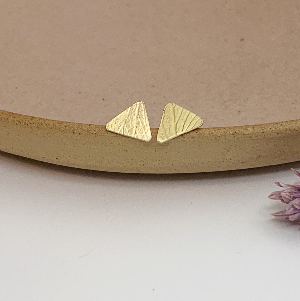 Image of Brass triangle studs with petal imprint. 