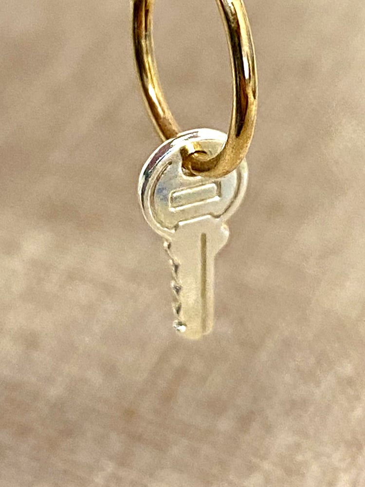 KEYS SYMBOLISE FREEDOM, THEY OPEN UP AND LOCK PRECIOUS THINGS AWAY. KEYS LET US INTO UNKNOWN WORLDS. 
It is a pathway, freedom, an expression of desire to open up the world.
The opening of many exciting doors to come.

The unlock earring features a small key charm pendant 18 mm - 0,7", which is carried by a delicate tiny hoop, available in 13 and 15mm - 0,5 and 0,6" diameter. (model is wearing 13mm hoop) Inform us when placing an order.

Notably, the key is detailed ...