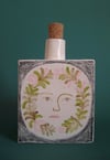 Flower face ceramic bottle with stopper.