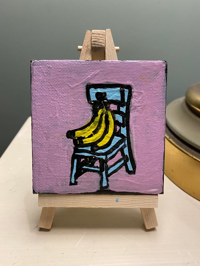 Image of enormous bunch of bananas on a tiny blue chair