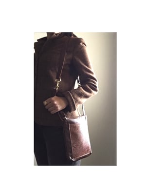 Image of crossbody with embossed leather and brass swivel snaps