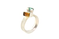 Image 1 of A contemporary ring featuring Orange Tourmaline and emerald in a silver claw setting