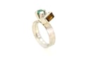 A contemporary ring featuring Orange Tourmaline and emerald in a silver claw setting