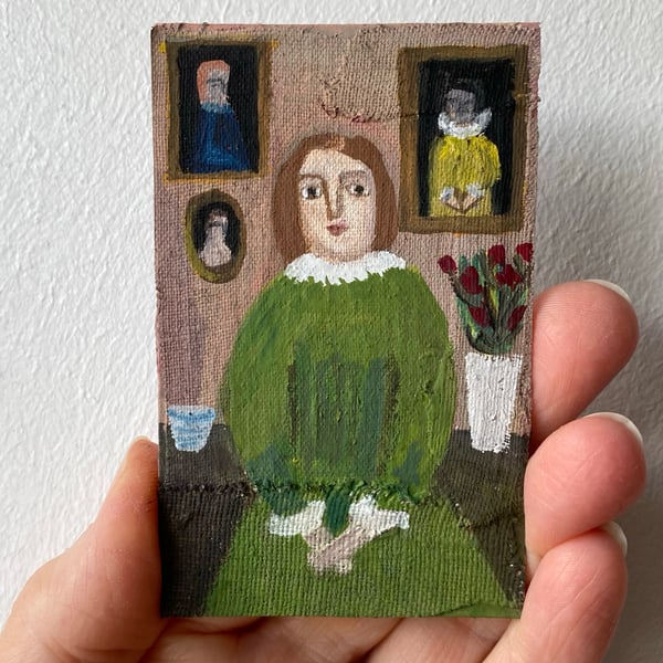 Image of young woman in green with paintings 