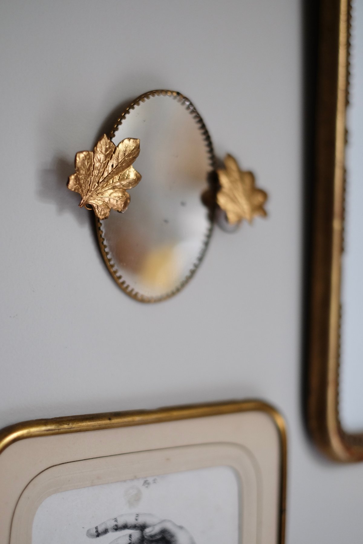 Image of Miroir ovale orné de feuilles.