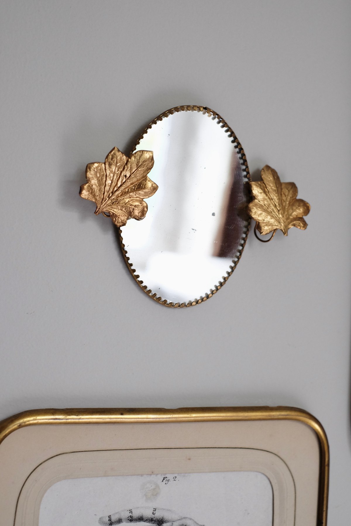 Image of Miroir ovale orné de feuilles.