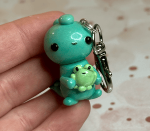 Image of Dino Holding A Frog Charm