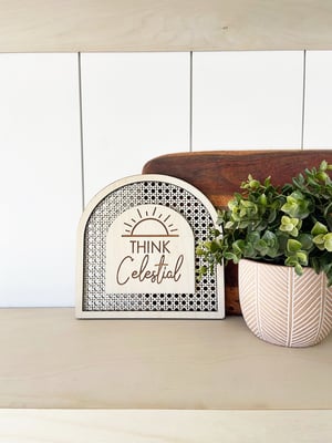 Image of “Think Celestial” faux rattan shelf sign