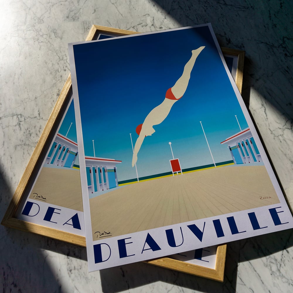 A sleek and sunlit travel poster by Razzia celebrating Deauville, the iconic seaside resort on the Normandy coast of France. The artwork features a minimalist composition with a diver captured mid-flight against a vast, cloudless blue sky. Below, the geometric symmetry of the beach promenade and seaside cabins evokes the timeless elegance of Deauville’s famous boardwalk. The figure, rendered in soft tones with a red bathing cap and swimwear, adds a dynamic contrast to the serene architectural setting. The bold typography DEAUVILLE anchors the image with understated sophistication. Razzia’s clean lines, balanced composition, and striking use of color perfectly capture the glamour and leisure of French coastal life, transforming a fleeting summer moment into a work of enduring style and grace.