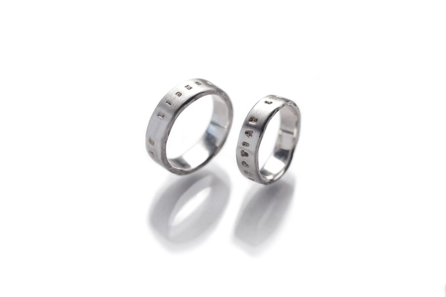 Image of silver wedding rings with inscription in Latin