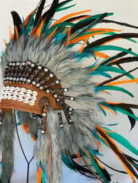 Tan, orange, green headdress with cowrie shell