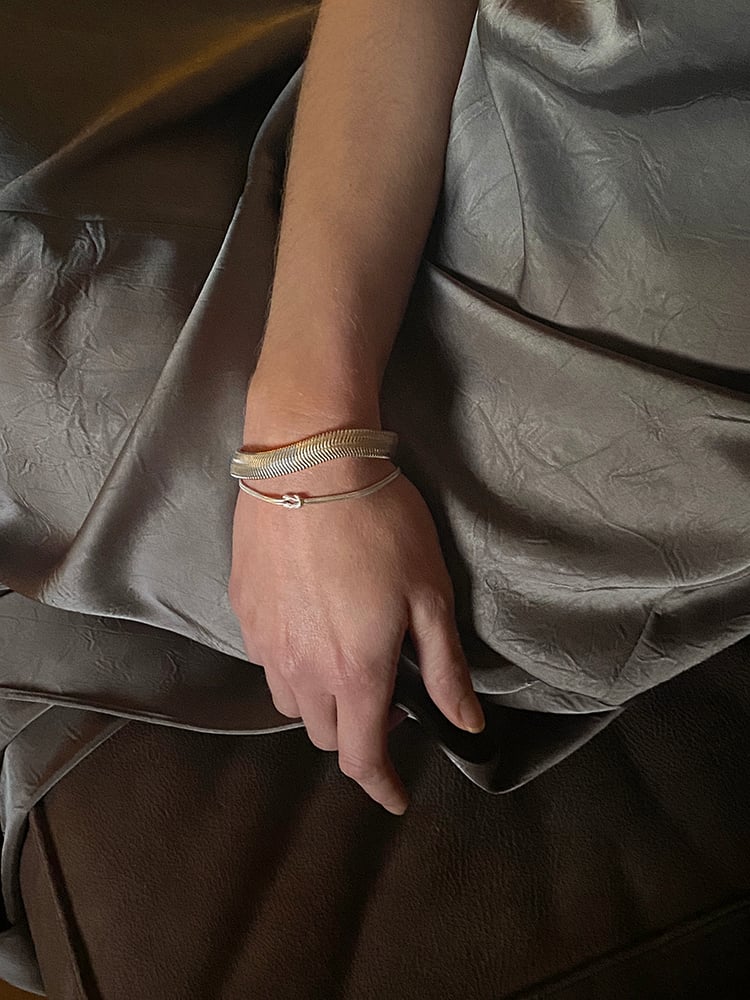 A TINY PRESENCE THAT FEELS LARGER

IT REMINDS YOU OF THE WARMTH OF SHARED MEMORIES,
THE BONDS THAT MATTER MOST

Two 925 sterling silver thin round chains intertwined which can move fluidly.
Adjustable in length

This bracelet is subtle and refined, an elegant opulent touch of silver addition to any outfit.
 