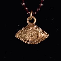 Image 1 of Bronze Averting Eye pendant on a string of garnets.