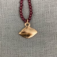 Image 3 of Bronze Averting Eye pendant on a string of garnets.