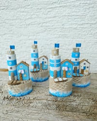 Image 1 of In the blue sea, in the white foam Lighthouse and driftwood house