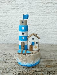 Image 3 of In the blue sea, in the white foam Lighthouse and driftwood house