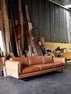 CLOVER COUCH IN TASMANIAN OAK WITH UPHOLSTERED SIDES IN TOBACCO LEATHER