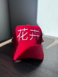 Image 1 of “Flowers”  in Chinese, red corduroy hat. 