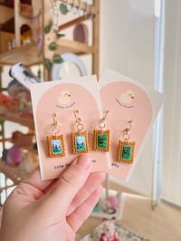 Image 1 of cottage core tiny paintings dangle earrings | cat, forest, river