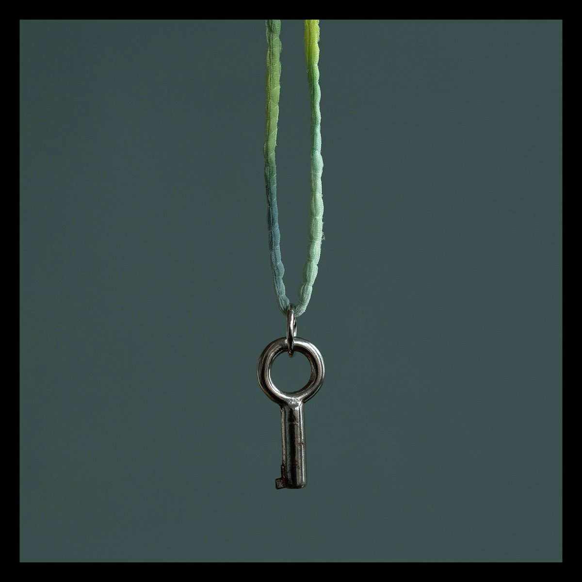 Small circular barrel key on silk "Chameleon" cord