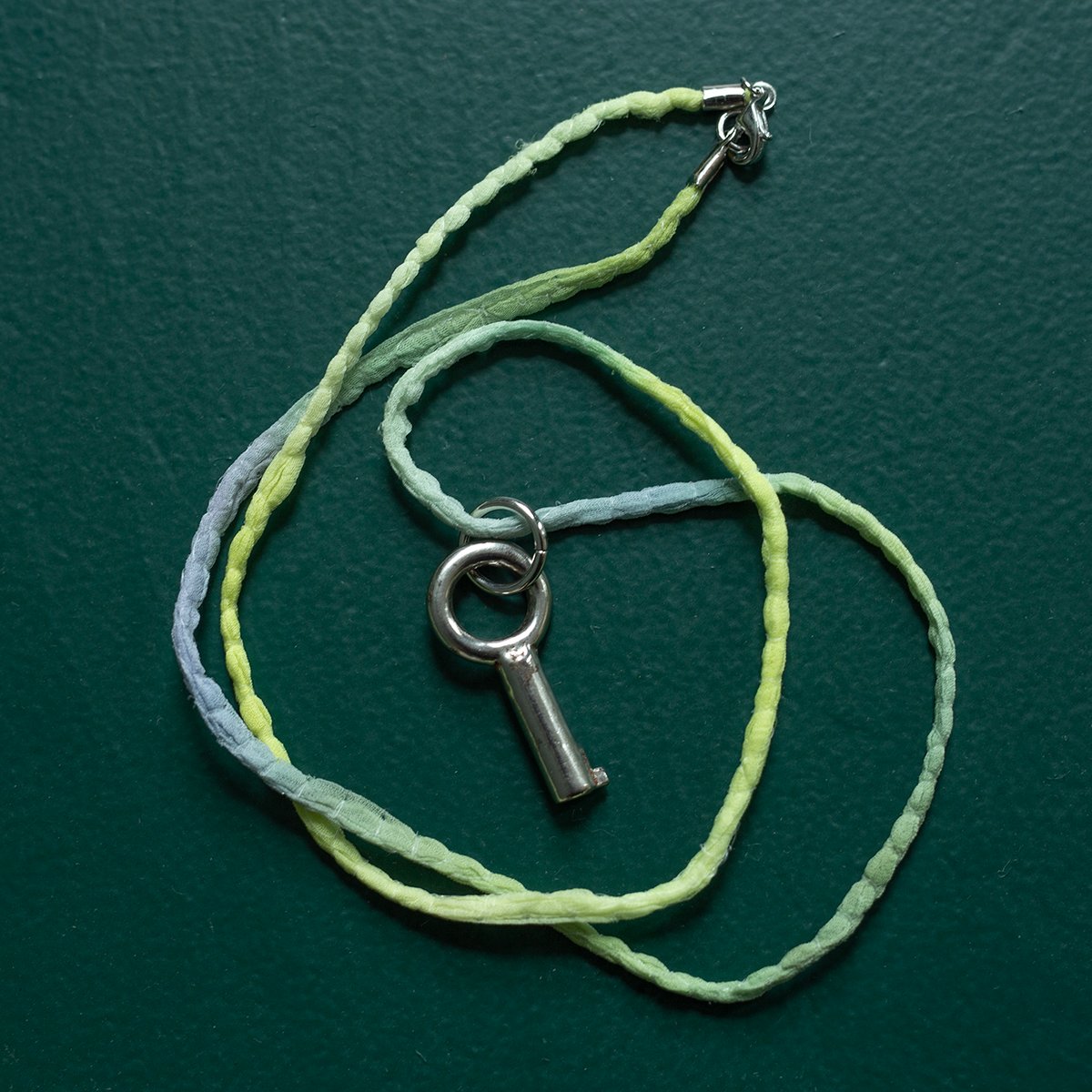 Small circular barrel key on silk "Chameleon" cord