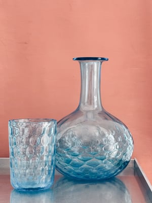 Blå sengekants karaffel med glas. 