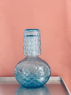 Blå sengekants karaffel med glas. 