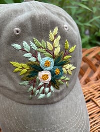 Image 1 of Blue hand embroidered flowers on an adjustable khaki colour hat