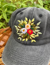 Image 1 of Light blue, pink, and red hand embroidered flowers on an adjustable dark grey hat