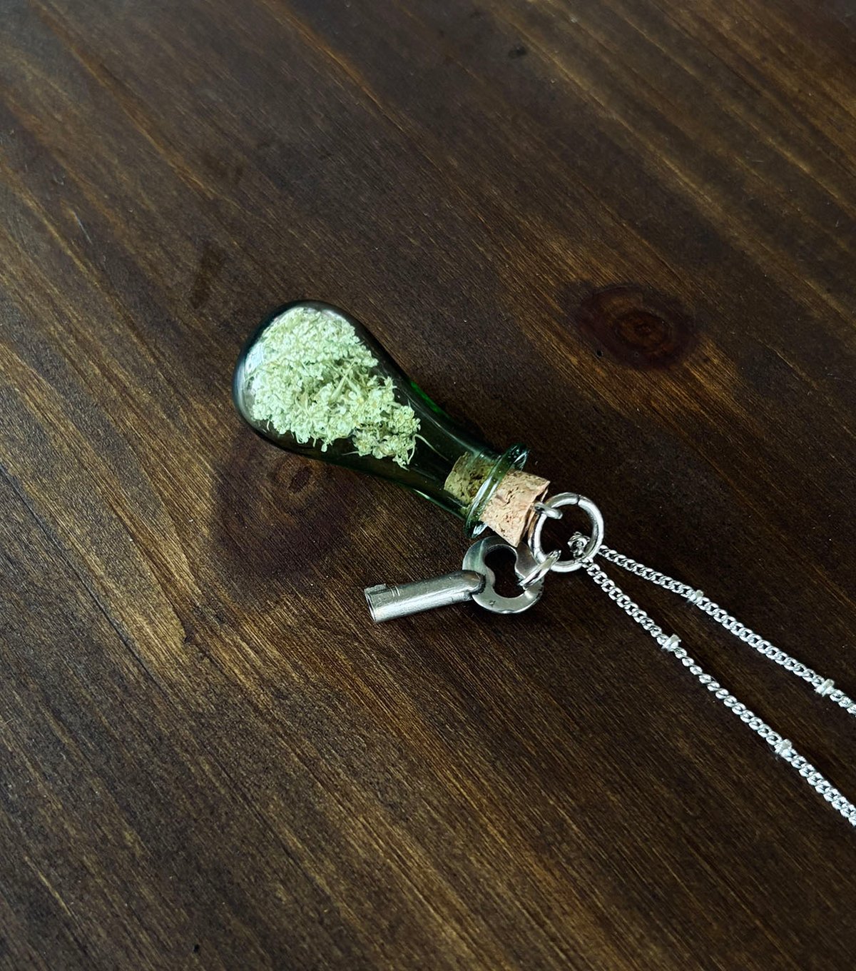 Green vial of Queen Anne's lace with tiny key 