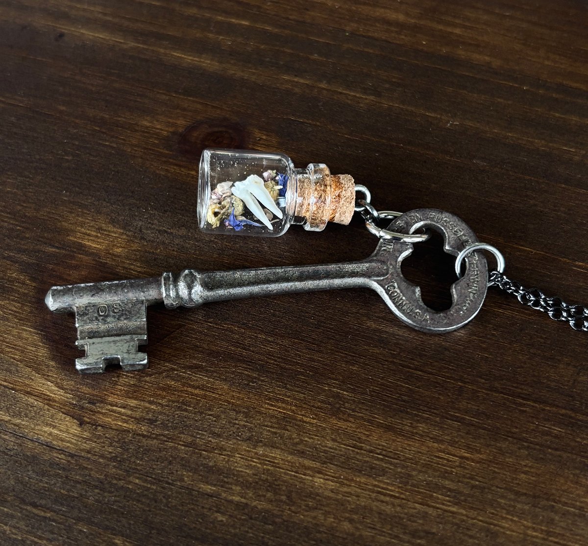 Victorian era key with vial of opossum tooth & dried florals