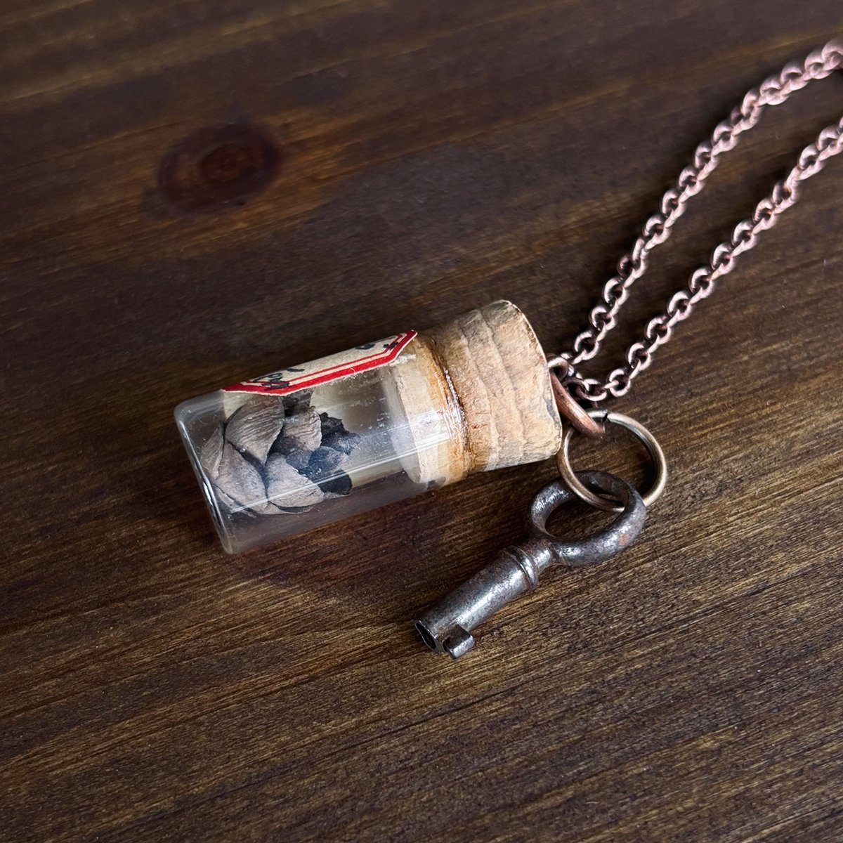 Tiny round key with pinecone in antique Elgin watch parts vial