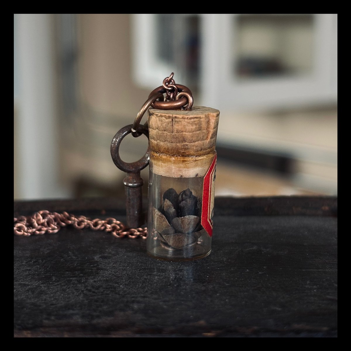 Tiny round key with pinecone in antique Elgin watch parts vial