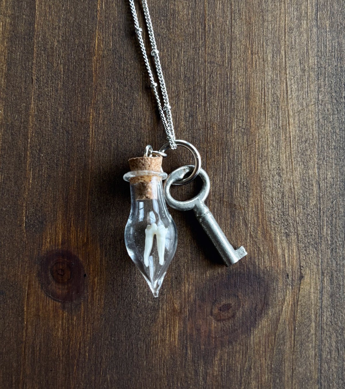 Small key with opossum tooth in teardrop vial