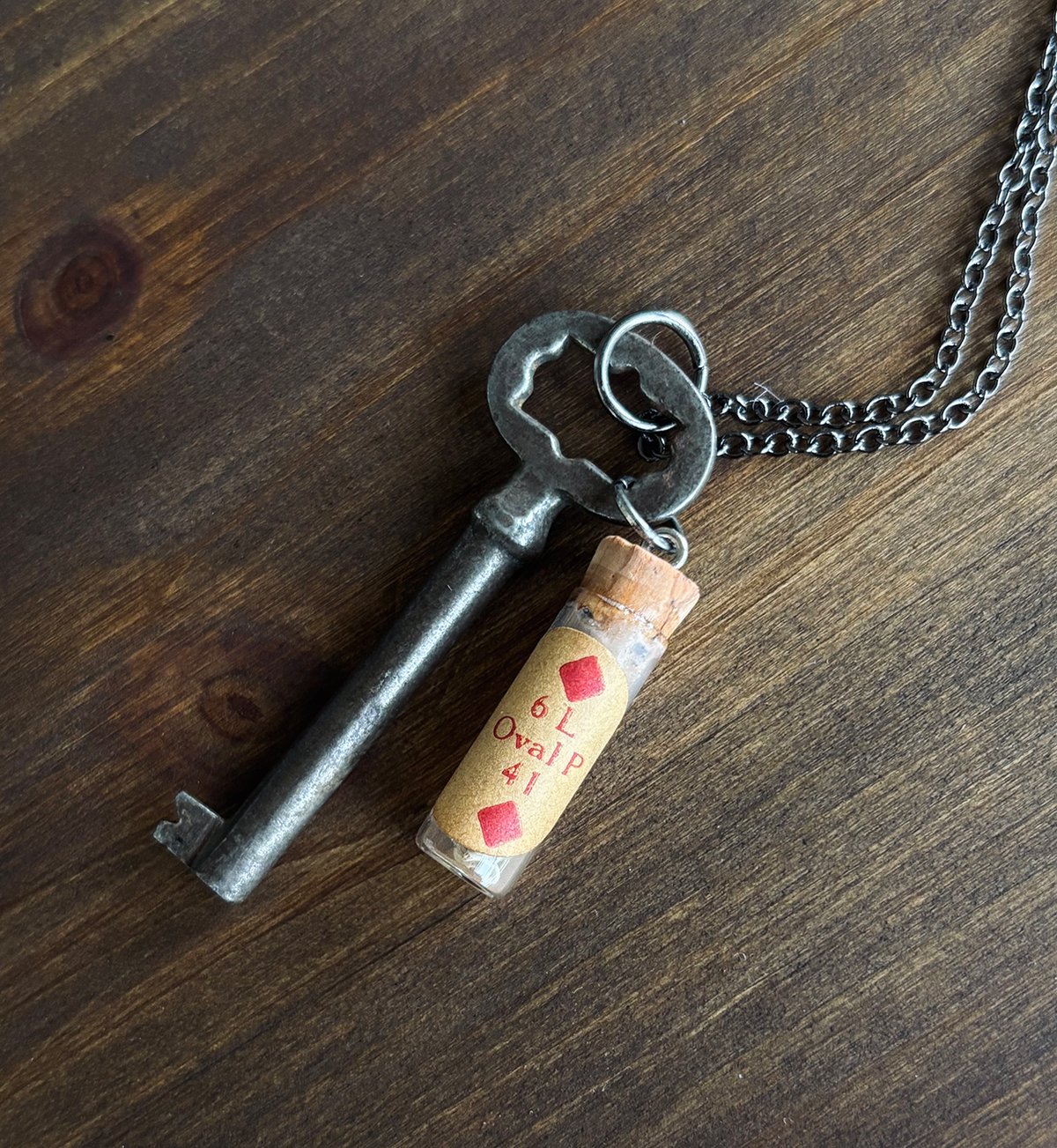 Key with rat vertebrae in vintage clock parts vial