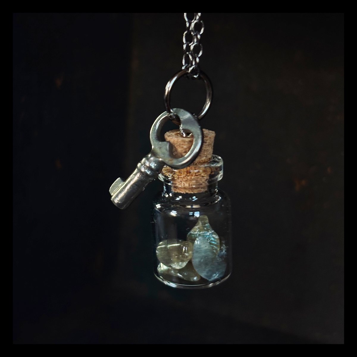Tiny key with labradorite crystals in glass vial