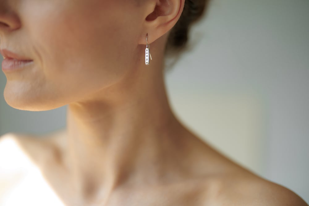 Image of light plain silver earrings with inscription in Latin