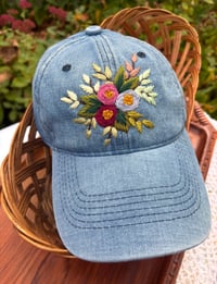 Image 4 of Dark maroon, pink, and light purple hand embroidered flowers on an adjustable medium blue colour hat