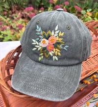 Image 1 of Dark, medium and light pink hand embroidered flowers on an adjustable dark green fabric hat