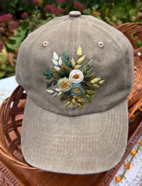 Image 2 of Blue, white, and light green hand embroidered flowers on an adjustable khaki fabric hat