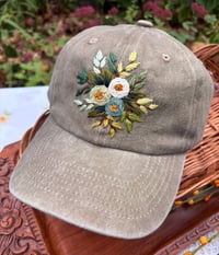 Image 1 of Blue, white, and light green hand embroidered flowers on an adjustable khaki fabric hat