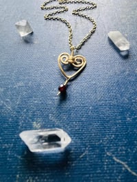 Image 3 of wire wrapped heart with tiny garnet in gold